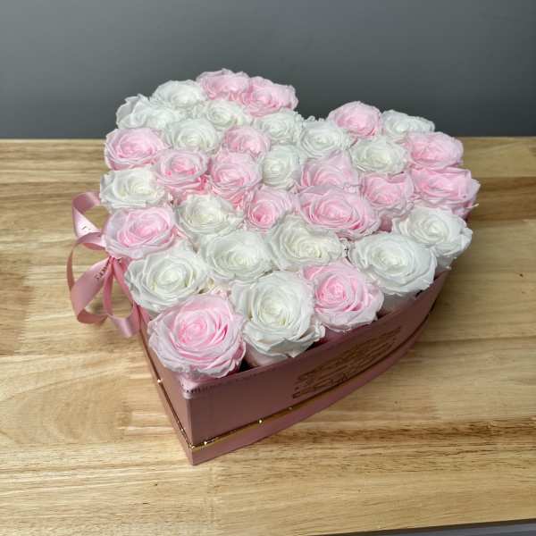Heart-shaped box of pink and white roses with a ribbon bow