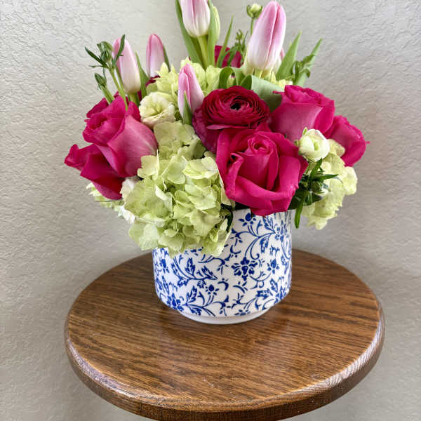 Pink roses and tulips arranged in a blue-and-white ceramic vase