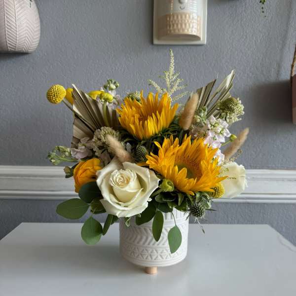 Yellow and white floral arrangement in a white ceramic pot