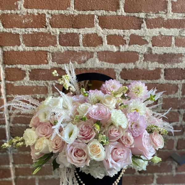 Pink and white rose bouquet in a black hatbox with pearl strands