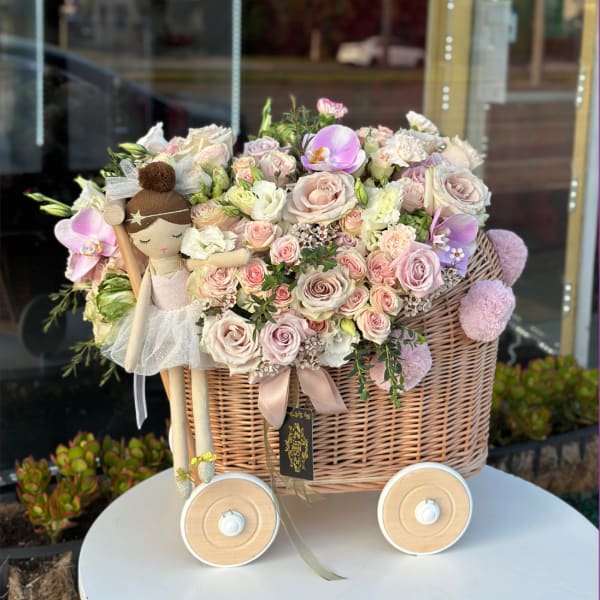 Pastel rose bouquet in a wicker basket with a doll decoration