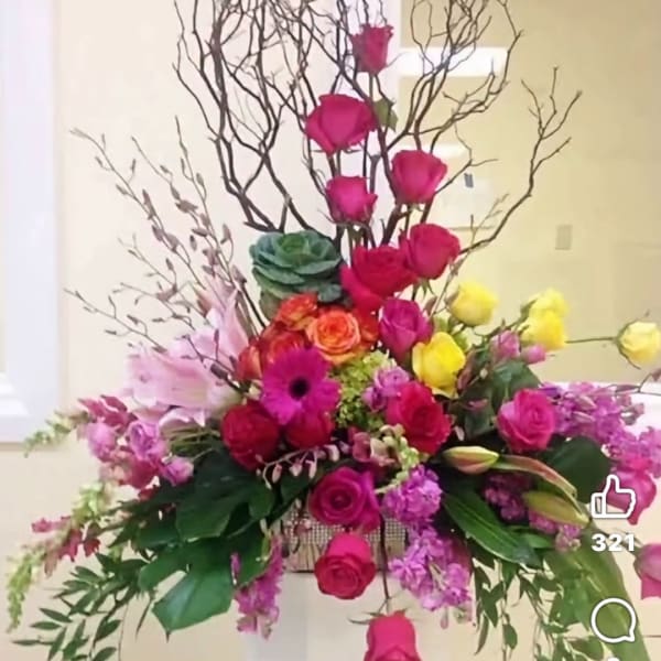 Tall mixed flower arrangement with bright roses and branches