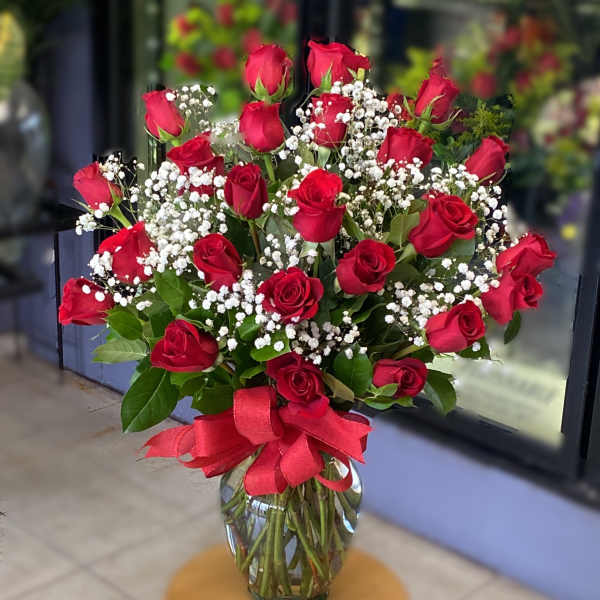Bouquet of red roses and baby's breath in a glass vase with a red ribbon