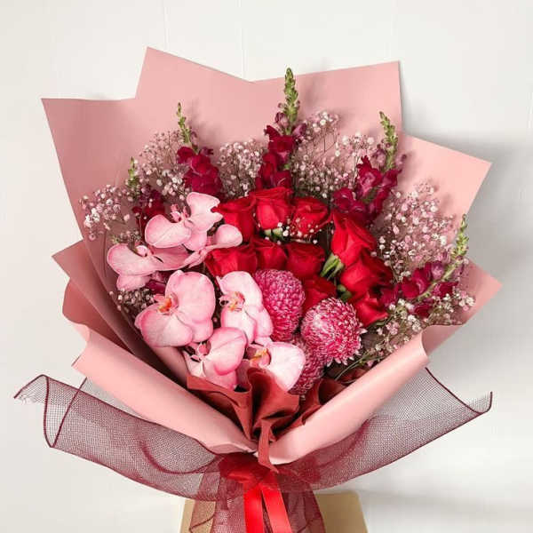 Bouquet of red roses and pink orchids wrapped in pink paper
