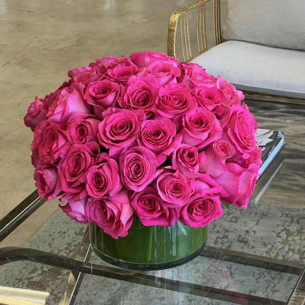 Round bouquet of bright pink roses in a green glass vase