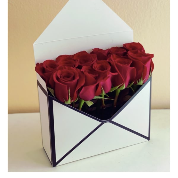 Red roses arranged in a white envelope-style box