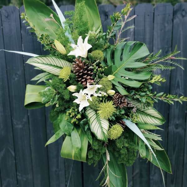 Tropical green floral arrangement with white lilies and pinecones