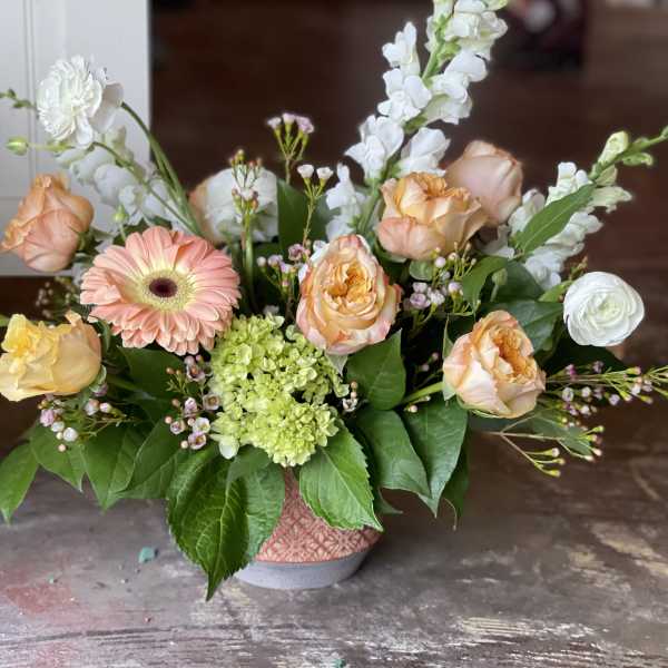 Peach roses and a pink gerbera daisy in a low vase arrangement