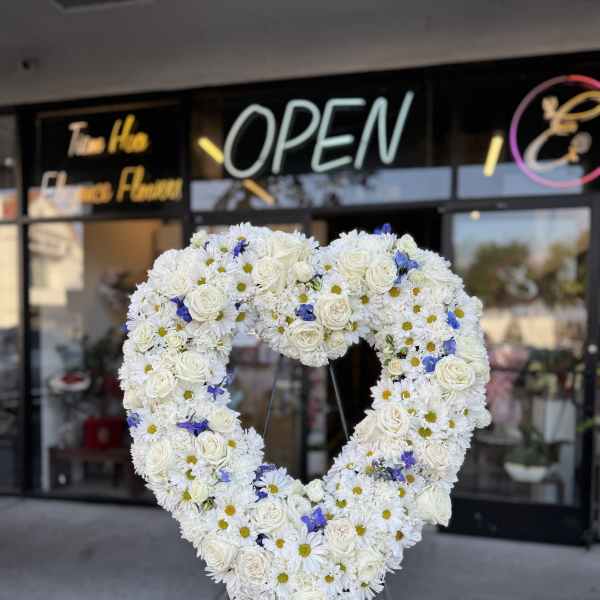 Heart-shaped floral wreath of white roses and daisies with blue accents