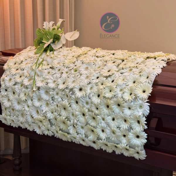 White flower-covered casket with a small white floral spray