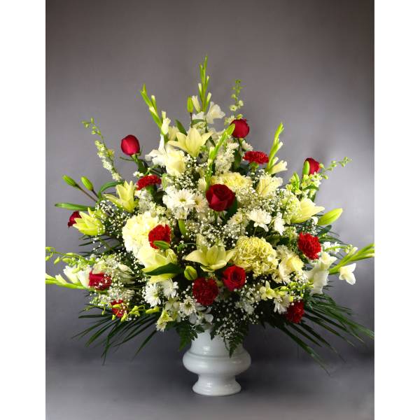 Large red, white, and yellow floral arrangement in a white vase