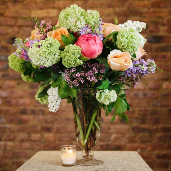 Mixed bouquet in a glass vase with pink, peach, and green blooms