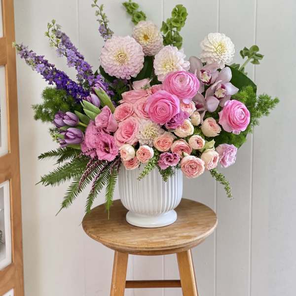 Pink and purple mixed flower arrangement in a white vase