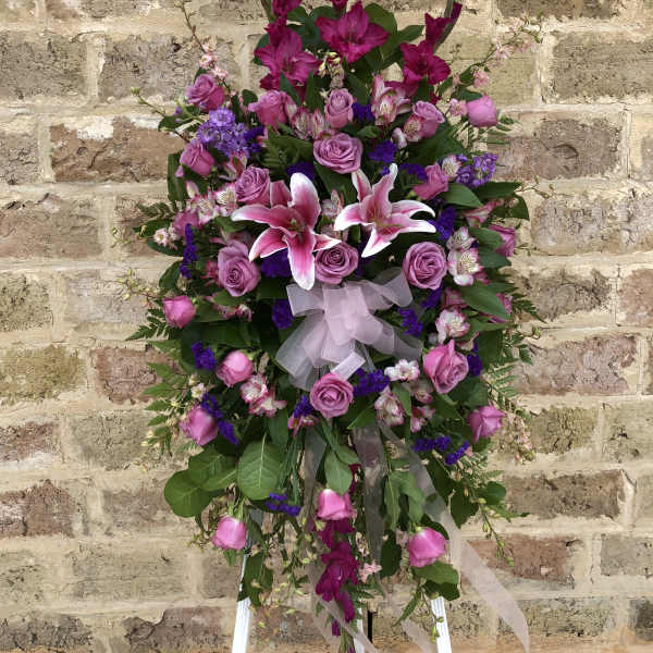 Standing floral spray with pink roses and lilies on a white easel