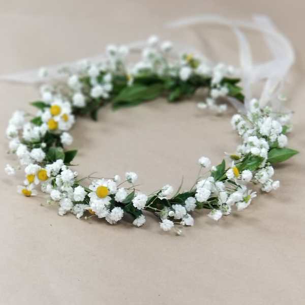 White floral crown with small yellow daisies on a ribbon tie