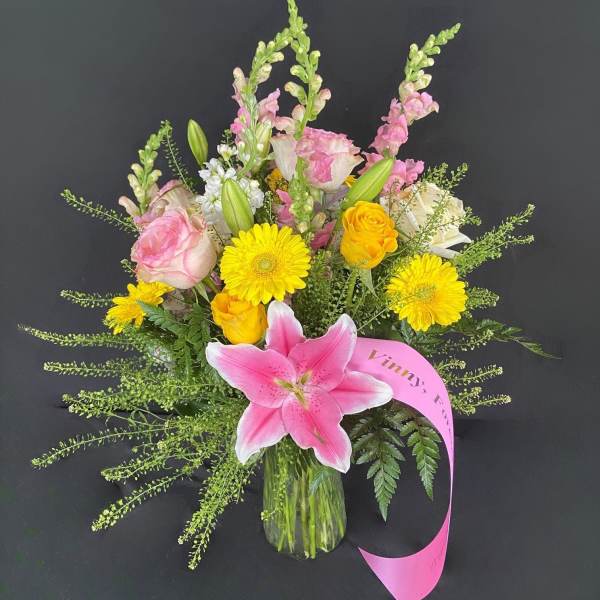 Pink lily bouquet with yellow daisies and roses in a glass vase