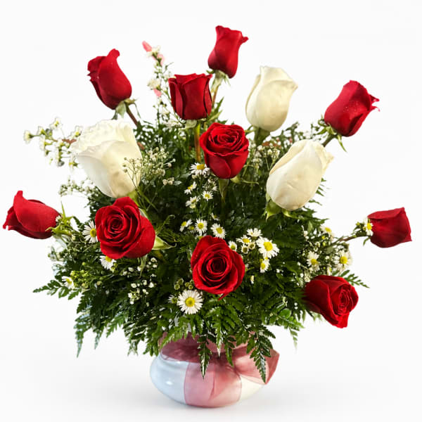 Red and white roses arranged in a round vase with small white daisies