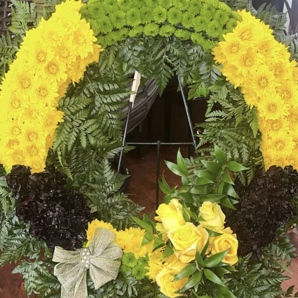 Yellow floral wreath with roses and chrysanthemums on a stand