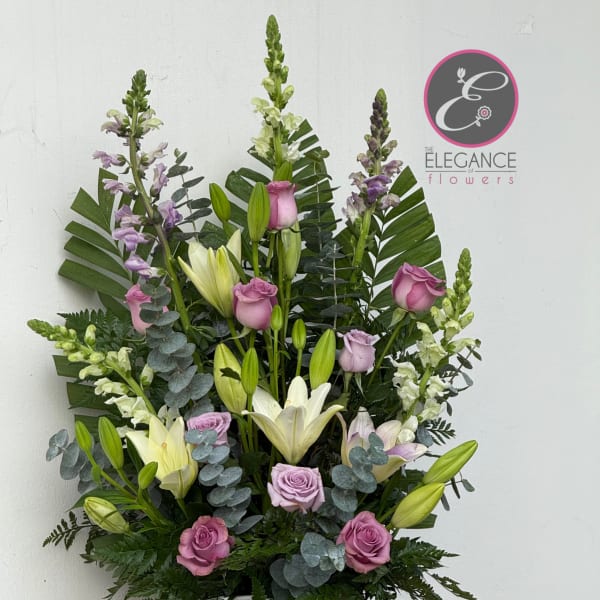 Tall arrangement of pink roses and white lilies in a white urn