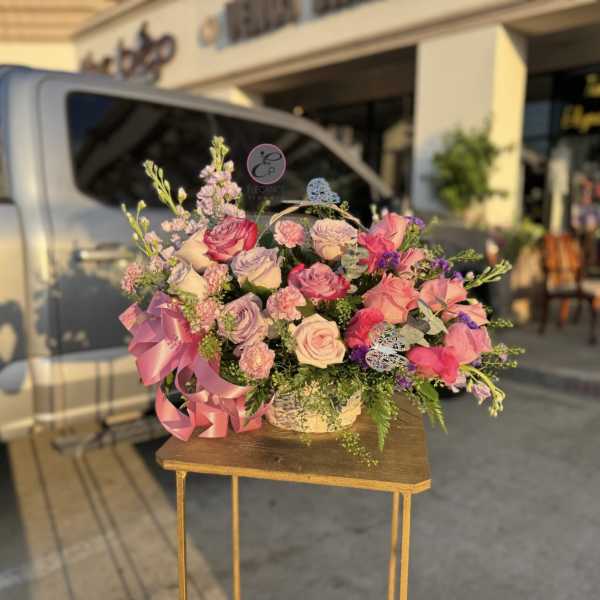 Pink and lavender rose arrangement in a basket with a ribbon