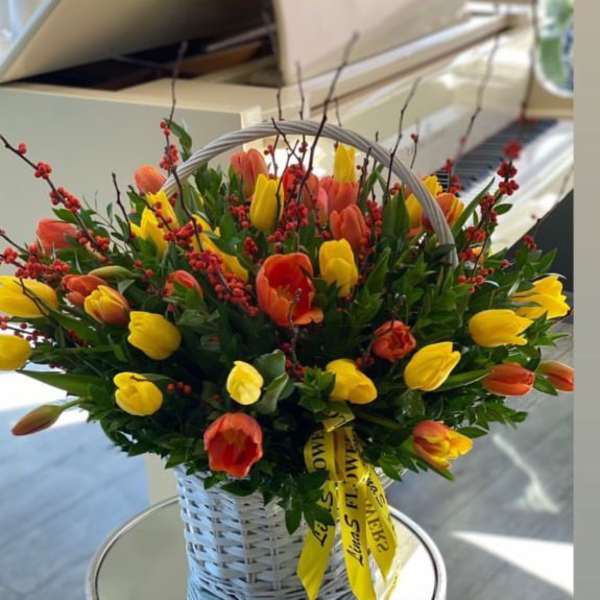 Basket of yellow and orange tulips with red berry branches
