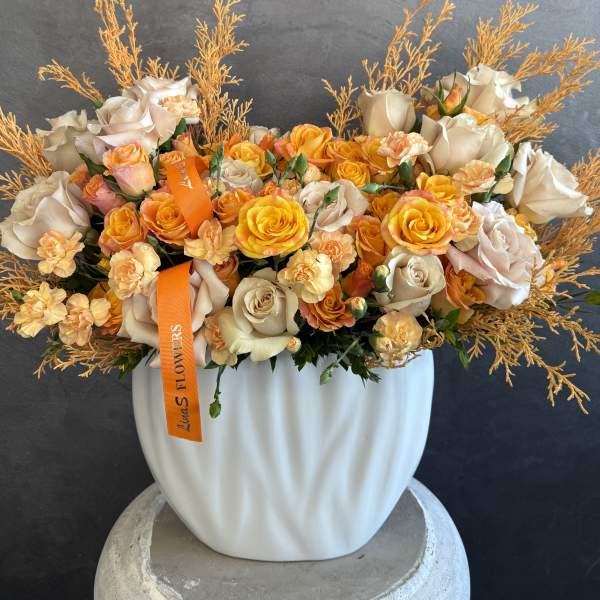 Bouquet of cream and orange roses in a white vase