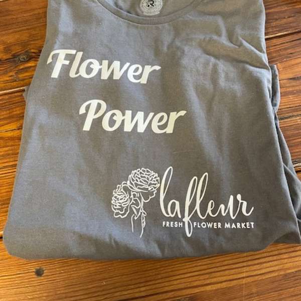 Folded gray T-shirt with white flower-themed text and graphic