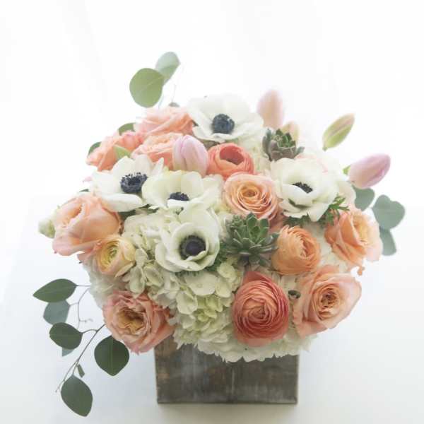 Peach and white floral arrangement in a square wooden container