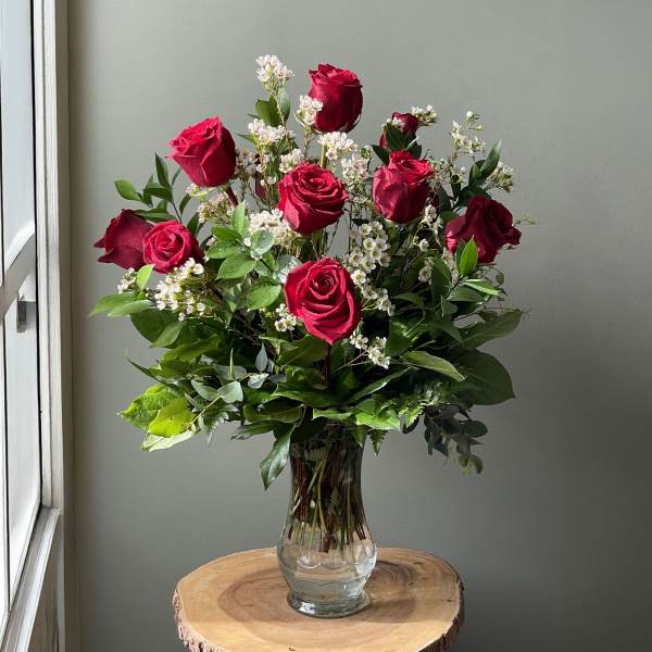 Bouquet of red roses and white filler flowers in a clear glass vase