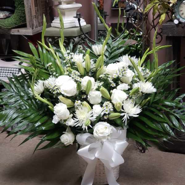 White roses and lilies in a basket with a white ribbon