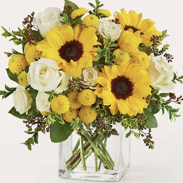 Yellow sunflowers and white roses in a clear glass vase