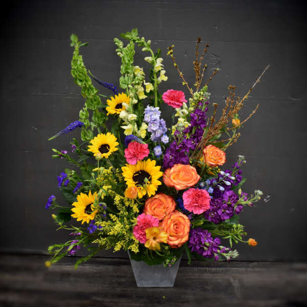 Colorful mixed flower arrangement in a gray vase with sunflowers and roses