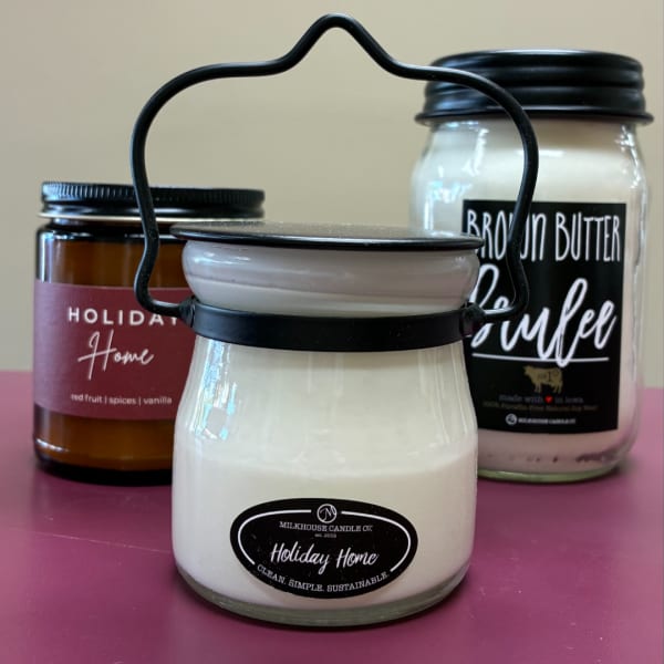 Three scented candles in glass jars, one with a metal handle in front