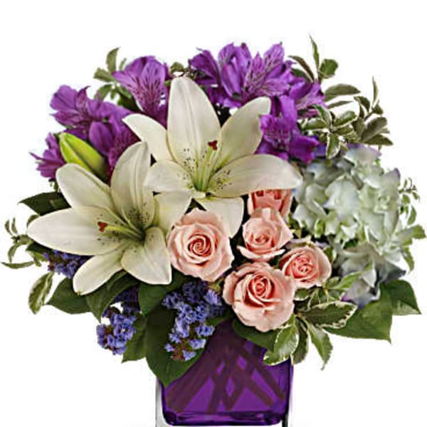 Bouquet of white lilies, pink roses, and purple flowers in a purple vase