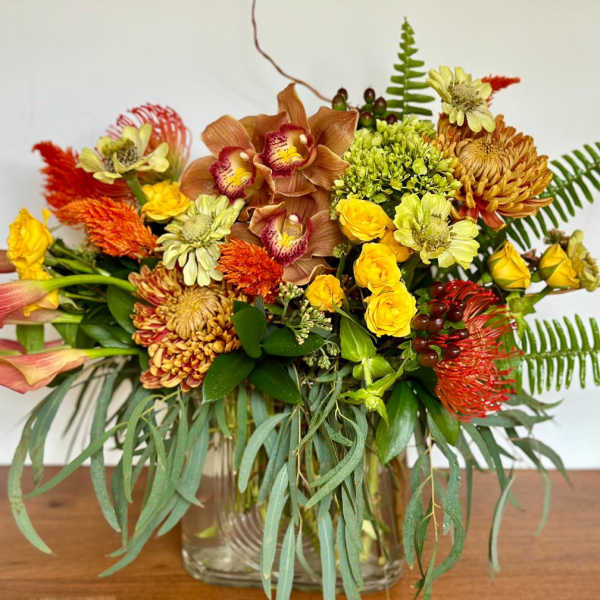 Mixed bouquet in a clear glass vase with yellow, orange, and pink blooms