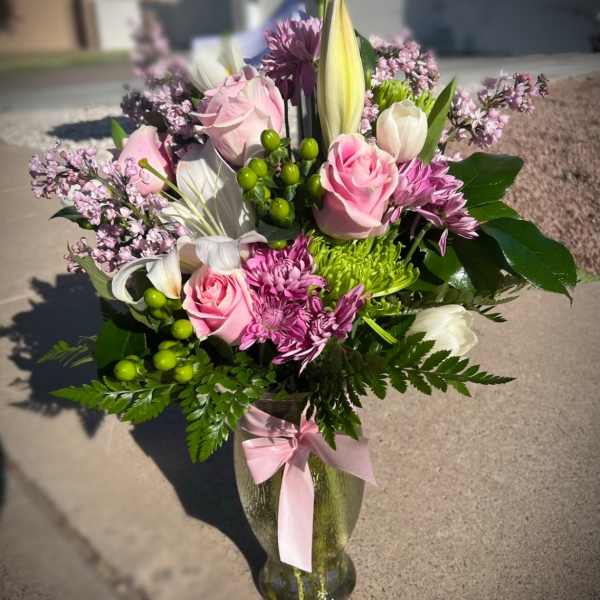 Pink and white mixed bouquet in a glass vase with a pink ribbon