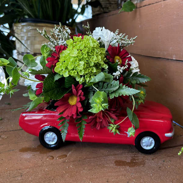Red flower arrangement in a toy car planter