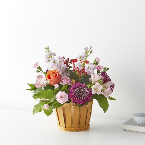 Mixed pink and purple flowers in a wooden basket