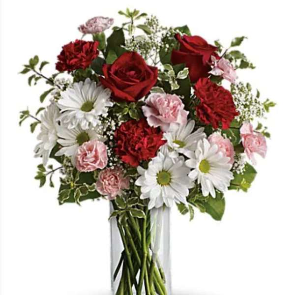 Bouquet of red roses, white daisies, and pink carnations in a clear glass vase