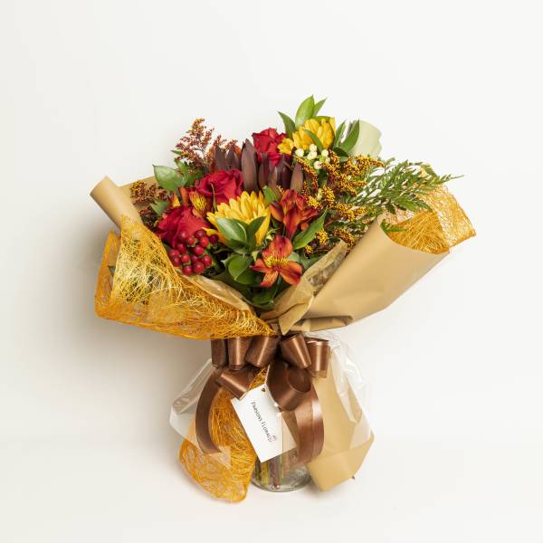 Bouquet of red roses and yellow flowers wrapped in tan paper