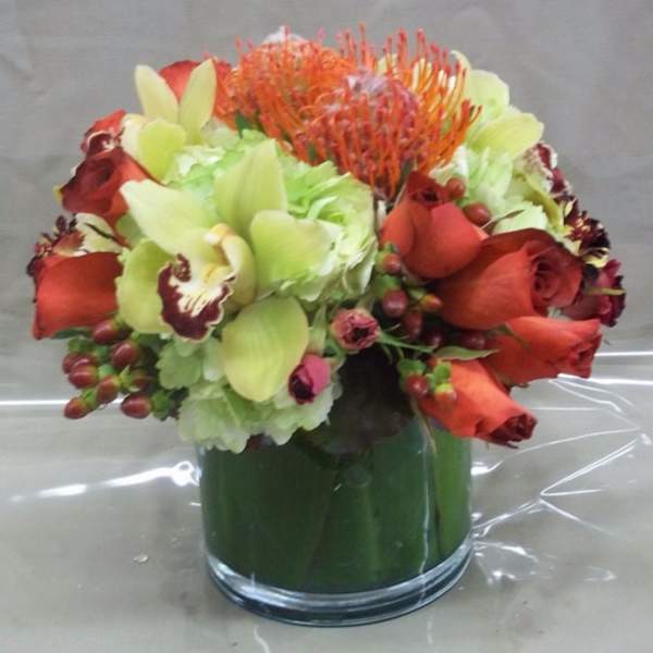 Orange and red floral arrangement in a glass vase