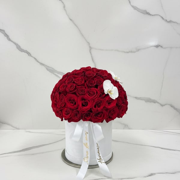 Round bouquet of red roses in a white hat box with white orchids