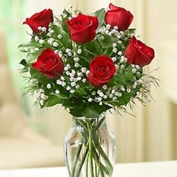 Red roses arranged in a clear glass vase with baby's breath