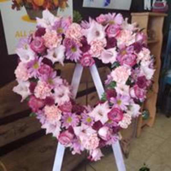Heart-shaped pink and white floral wreath on a white easel