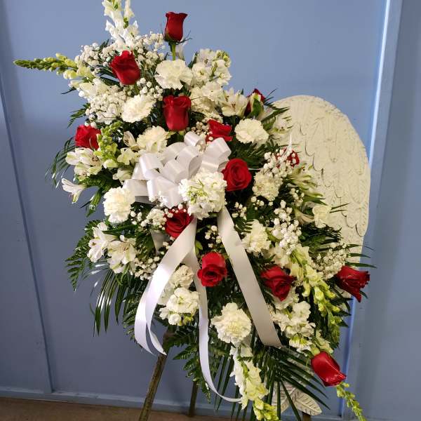 Standing floral spray with red roses and white flowers on an easel