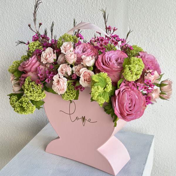Pink rose bouquet in a heart-shaped box with green accents