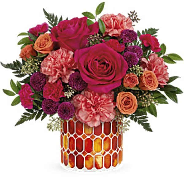 Bouquet of pink and orange flowers in a patterned glass vase