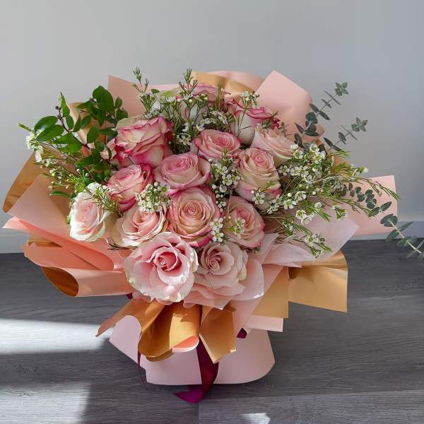 Pink and cream rose bouquet wrapped in peach paper