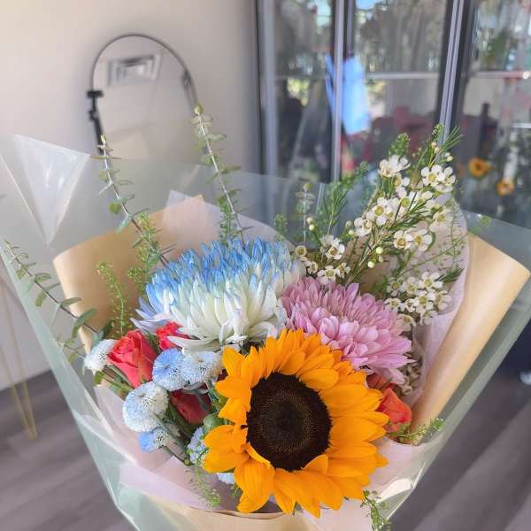 Bouquet with a sunflower, pastel chrysanthemums, and small white blossoms