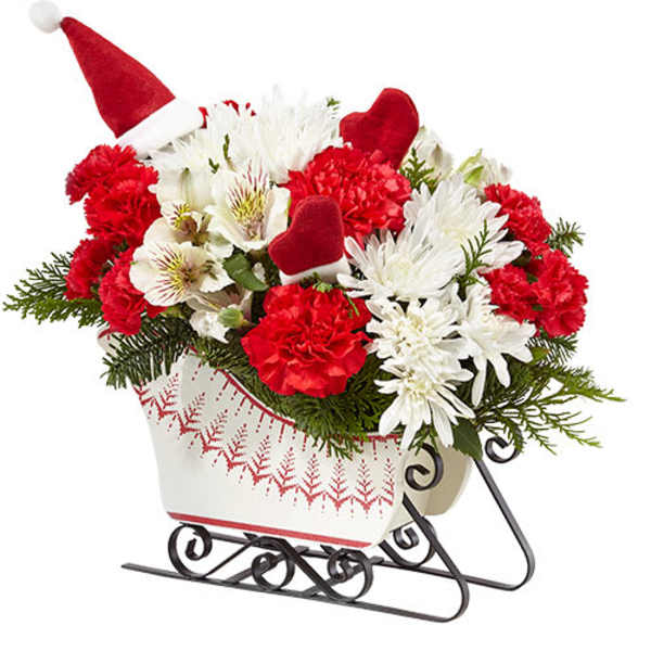 Red and white floral arrangement in a sleigh-shaped container with Santa hats